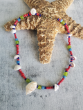 Colorful beaded necklace with shells on a textured surface