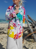 Person wearing a colorful tie-dye shirt on a beach