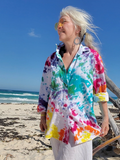 Person wearing a colorful tie-dye shirt on a beach