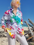 Person wearing a colorful tie-dye shirt on a beach