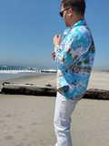 Person wearing a tie-dye shirt and sunglasses on a beach