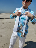 Person on a beach wearing a colorful shirt and sunglasses, with a clear blue sky.