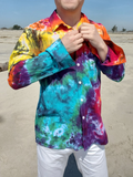 Person wearing a colorful tie-dye shirt outdoors on a sandy background