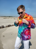 Person wearing a tie-dye shirt and sunglasses on a beach