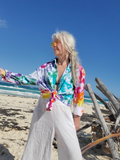 Person wearing a colorful tie-dye shirt and sunglasses on a beach