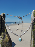 silver pearls adjustable necklace with a blue pendant laying at the beach