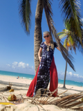 Woman in a dress standing on a tropical beach with palm trees and clear blue sky.