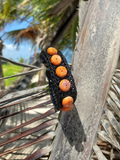 Black bracelet with orange beads on a branch