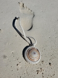 Necklace with a circular pendant on a sandy surface