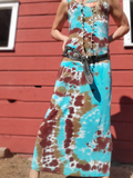 Woman wearing a tie-dye dress with a belt in front of a red wooden wall.