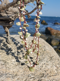 layering necklace, hanging on a branch, shot with the ocean on the back