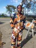 Person wearing a tie-dye outfit standing outdoors on a sidewalk.