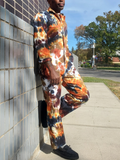 Person wearing a tie-dye outfit leaning against a wall outdoors.