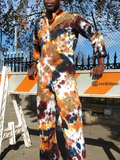 Person wearing a tie-dye jumpsuit standing behind a Con Edison barrier.
