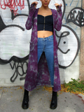 A front shot, cardigan open, Mariana is holding up both of her arms, fingers in the thumbholes. The hand dyed garment has an uneven distressed color; mostly purple with lighter greyish areas.