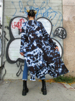 Back view of Mariana who's modeling this hand dyed black long duster. She is wearing a crop top, combat boots and skinny jeans with this piece. The wind is blowing the light weight cardigan a bit.