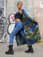 Mariana's killer pose; she has a wide step, standing sideway, looking back. She's  wearing a crop top, blue skinny jeans and combat boots, the hand dyed cardigan is done in olive navy colors, floating in the back of her.