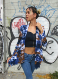 She's wearing a crop top, pair of blue skinny jeans and boots with tis hand dyed cardigan; dark earthy colors - navy-lapis-khaki. Here she looks to the right, the cardigan is open, she's holding the asymmetrical hem a bit out to show the shape.