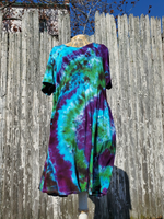 Displayed on a form, standing front of our fence, a shor; pockets, V-neck, hand dyed in purple-green-jade and a little black.ss or tunic