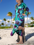 I'm leaning up against a palm tree, with sand under my feet; I'm wearing a long sleeve hooded dress with side slits, V-neck and a hood. I dyed this dress in my Northern Lights combo; purple-green-jade and a bit if black. A somewhat side view.